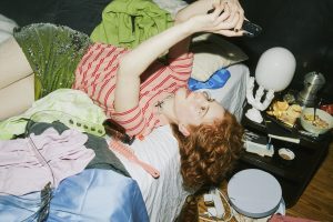 Frau liegt auf vollem Bett und shoppt online