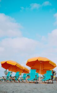 Gelbe Sonnenschirme, mit türkisen Liegestühlen am Strand